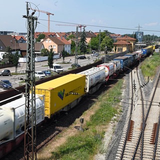 Auf der Bahnstrecke Karlsruhe-Mannheim fährt ein Güterzug an Häusern vorbei. 