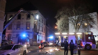 Mehrere Feuerwehrfahrzeuge unter anderem mit einer Drehleiter stehen vor dem Haus, in dem es gebrannt hat