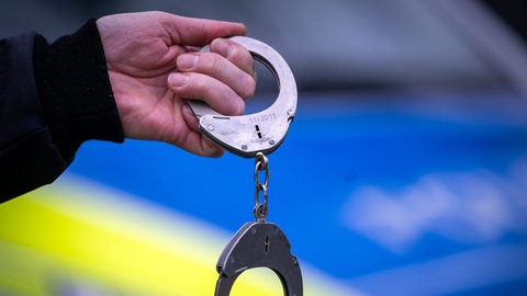 Polizist mit Handschellen (Symbolbild)