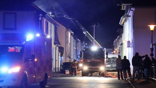 Ein Feuerwehrauto mit einem Leiterwagen steht vor dem Haus in Oftersheim