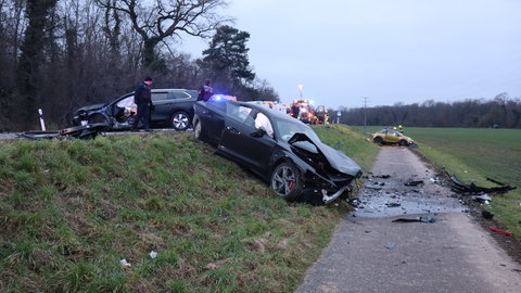 Mehrere Autos, die  beim Unfall beschädigt wurden, stehen an einer Böschung. Rettungskräfte sind im Einsatz.