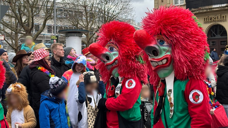 Zwei große Figuren haben rote Haare, grüne Gesichter und riesige, gerötete Nasen.