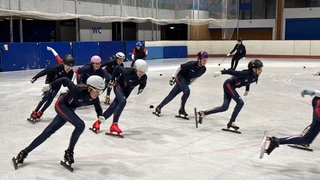 Die Sportlerinnen fahren über das Eis.