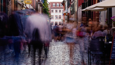 Menschen laufen am Abend in der Heidelberger Innenstadt durch die Untere Straße. 