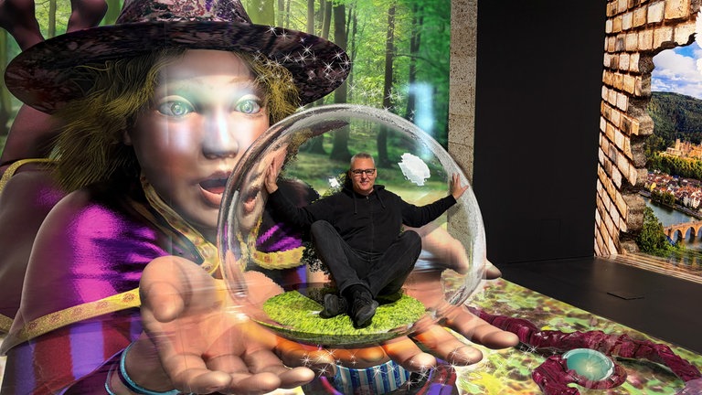 Es sieht so aus, als ob der Gründer des "TrickArt Museums" Heidelberg in einer Kristallkugel sitzt, die sich in den Händen einer Hexe befindet.