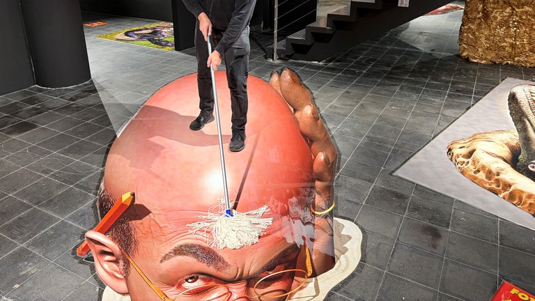 Es sieht so aus, als würde Museums-Gründer Guido Mülter auf einem Kopf stehen und ihn schrubben.