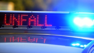 Symbolbild: Die blau leuchtenden Lichter eines Polizeiautos und die digitale Aufschrift "UNFALL". Auf der A6 bei Wiesloch ist es mutmaßlich zu einem illegalen Autorennen gekommen, bei dem eine 21-jährige Fahrerin durch einen Auffahrunfall leicht verletzt wurde.