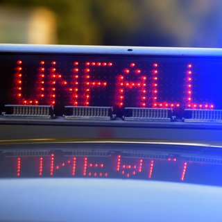 Symbolbild: Die blau leuchtenden Lichter eines Polizeiautos und die digitale Aufschrift "UNFALL". Auf der A6 bei Wiesloch ist es mutmaßlich zu einem illegalen Autorennen gekommen, bei dem eine 21-jährige Fahrerin durch einen Auffahrunfall leicht verletzt wurde.