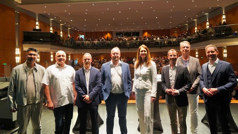 Die acht Kandidierenden der OB-Wahl in Weinheim auf der Bühne in der Stadthalle 