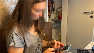Die Betroffene hält ihr Smartphone in der Hand und liest Nachrichten.