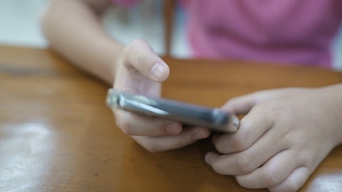 Nahaufnahme der Hände eines Mädchens, das ein Smartphone benutzt (Symbolbild).