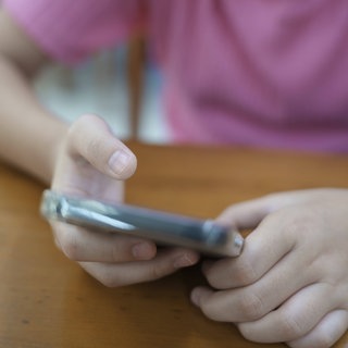 Nahaufnahme der Hände eines Mädchens, das ein Smartphone benutzt (Symbolbild).