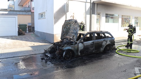 Ein Auto ist komplett ausgebrannt und schwarz vor Ruß.