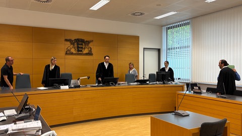 Das Gericht bei Beginn des Prozesses um sexuellen Missbrauch über Messengerdienste. Der Angeklagte hält sich eine Mappe vor das Gesicht.