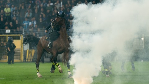 Berittene Polizeikräfte und weitere Einsatzkräfte sichern den Innenraum des Stadions, nachdem während des DFB-Pokalspiels zwischen SV Waldhof Mannheim vs Kaiserslautern. Pyrotechnik gezündet wurde.