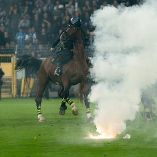 Berittene Polizeikräfte und weitere Einsatzkräfte sichern den Innenraum des Stadions, nachdem während des DFB-Pokalspiels zwischen SV Waldhof Mannheim vs Kaiserslautern. Pyrotechnik gezündet wurde.