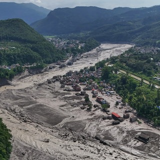 Nach Sturzfluten im nepalesischen Distrikt Nuwakot stehen beschädigte Häuser gefährlich nahe an den angeschwollenen, mit Treibgut verstopften Ufern des Trishuli-Flusses.