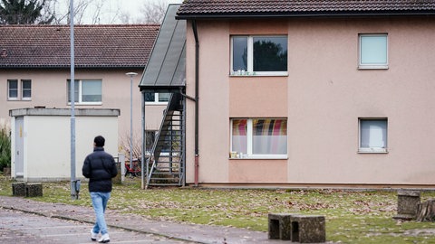 Ein Bewohner geht im Ankunftszentrum für Flüchtlinge auf dem Gelände der ehemaligen US-Militärfläche Patrick-Henry-Village an Wohnhäusern vorbei.