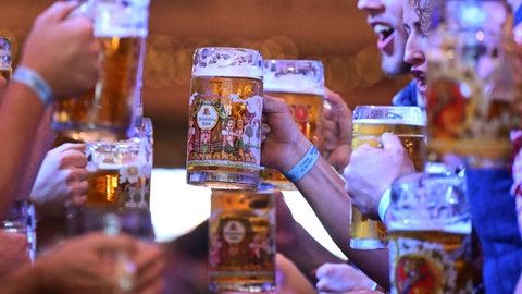 Gäste beim Frühlingsfest Stuttgart auf dem Cannstatter Wasen  stoßen im Festzelt mit Bier an. 