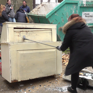Ein Frau schlägt mit einem Golfschläger auf ein Möbelstück ein: Der Rage Room Kornwestheim bei Stuttgart lädt dazu ein, mal alle Wut und Aggression rauszulassen. 
