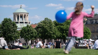 Ein Kind spielt auf dem Stuttgarter Schlossplatz mit einem Luftballon.