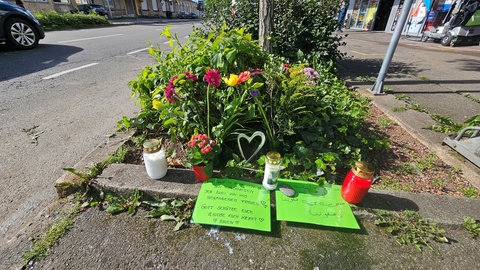 Blumen und Grablichter liegen und stehen an der Stelle in der Bahnhofstraße in Nürtingen, wo am Sonntag zwei Menschen bei einem Unfall ums Leben gekommen sind.