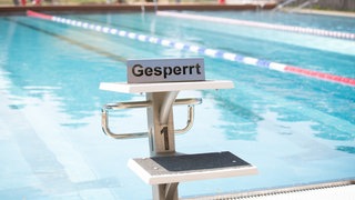 Ein Startblock am Freibadbecken mit einem "gesperrt"-Schild darauf. (Symbolbild)