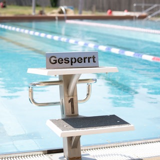 Ein Startblock am Freibadbecken mit einem "gesperrt"-Schild darauf. (Symbolbild)