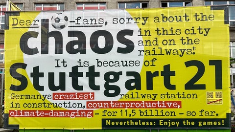 Am Stand der S21-Gegner prangt während der EM ein großes Plakat. Es weist die Fußballfans auf das Bahnchaos hin. 