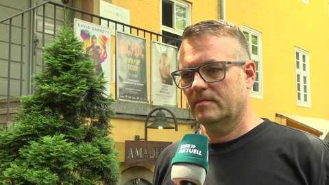 Paul Woog vom Veranstalter SKS Michael Russ spricht in ein Mikrofon des SWR.