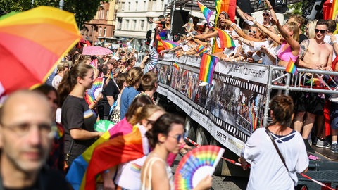 Menschen feiern mit Regenbogenflaggen den CSD in Stuttgart.
