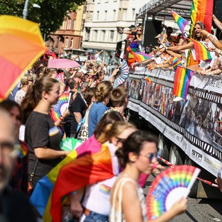 Menschen feiern mit Regenbogenflaggen den CSD in Stuttgart.