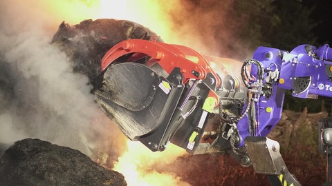 Mithilfe eines THW-Fahrzeugs werden brennende Heuballen bei Göppingen angehoben.