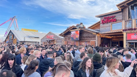 Das Bild zeigt Besucherinnen und Besucher des Cannstatter Volksfests 2024 auf dem Wasen.