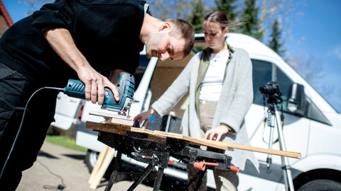 Junges Paar arbeitet mit Werkzeug am Ausbau eines Campers
