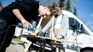 Junges Paar arbeitet mit Werkzeug am Ausbau eines Campers