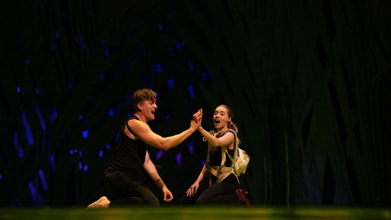 Tarzan und Jane schauen sich an, ihre Hände berühren sich und währenddessen singen sie. (Foto: SWR, Jakob Sax)