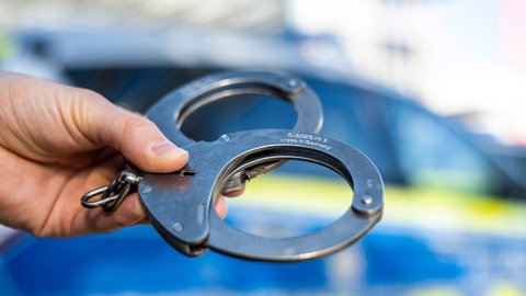 Symbolbild von Handschellen: Eine junge Frau sitzt in U-Haft, weil sie die Getränke von Kollegen mit Medikamenten versetzt haben soll.