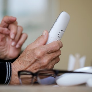 Masche Schockanruf: Eine ältere Dame nimmt in ihrer Wohnung ein Telefongespräch an (Symbolbild)
