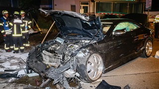 Rettungskräfte stehen an der Unfallstelle in Ludwigsburg neben dem Wrack einer der Limousine. Dieses war wohl wegen eines  illegalen Autorennens ins Fahrzeug zweier unbeteiligter Frauen gerast. Beide starben noch an der Unfallstelle.  