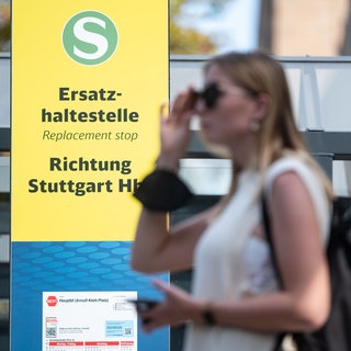 Eine Frau steht in Stuttgart vor einem Hinweisschild zu Schienenersatzverkehr: Wegen der für 2025 angekündigten Baustellen im Bahnnetz drängt der Verband Region Stuttgart die Deutsche Bahn, sich besser zu koordinieren und mehr Geld etwa für einen besseren Ersatzverkehr in die Hand zu nehmen.