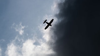 Ein Kleinflugzeug fliegt auf diesem Symbolbild vor dunklen Wolken. 