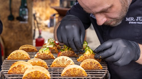 Ein Mann grillt kleine Tacos 