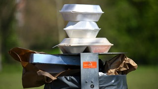 Leere Speise-Verpackungen stapeln sich in einem Park auf einem Mülleimer. Nachdem das Bundesverfassungsgericht in Karlsruhe die Verpackungssteuer in Tübingen gebilligt hat, wollen andere Städte nachziehen. 