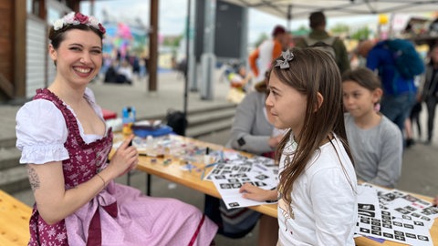 Anni Bork versorgt Klein und Groß beim ersten Familientag auf dem Stuttgarter Frühlingsfest mit bunten Glitzer-Tattoos.