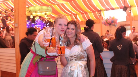 Carolin Kinzelmann aus Stuttgart und Lisa Kleindienst aus Marbach stehen am Mittwoch in einem Festzelt beim Stuttgarter Frühlingsfest und lächeln in die Kamera. 
