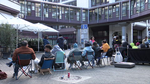 Menschen warten mit Kissen und Stühlen vor der Ausländerbehörde Stuttgart. (Archivbild)