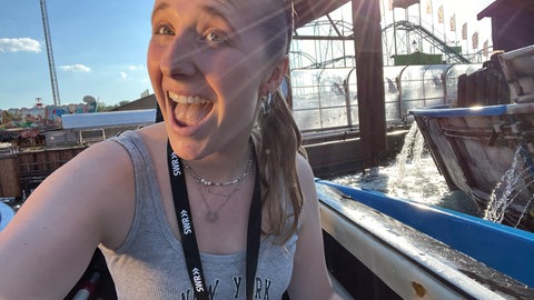 SWR Reporterin Anabel Giesbert sitzt in einer Gondel der Wildwasserbahn beim Stuttgarter Frühlingsfest.