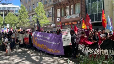 Zum "Tag der Arbeit" zieht der Demo-Zug Revolutionärer 1. Mai durch die Stuttgarter Innenstadt. Demonstrierende halten dabei Banner, Fahnen und Plakate.