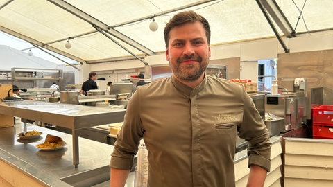 Matthias Kasprzyk ist Küchenchef im Göckelesmaier. Der 34-jährige steht am Tresen seiner Küche, seit 2022 arbeitet er auf dem Volksfest.